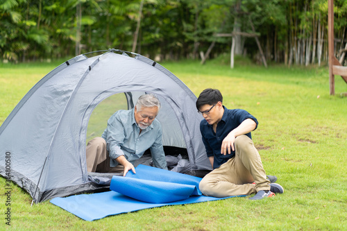 Senior Asian Father With Adult Son Enjoying Camping Holiday. senior mature father and smiling young adult Resting in the tent. Happy family time together.