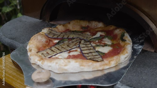 Chef puts grilled eggplants on top of Neapolitan pizza dough and rotates it on the tray. photo