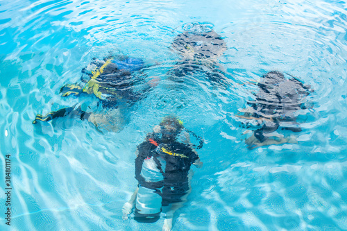 A diving instructor teaches a group of people how to behave underwater with scuba diving