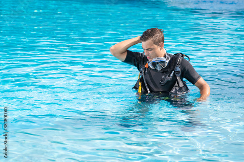Confused man exercising in the pool before scuba diving. He lost something in the water