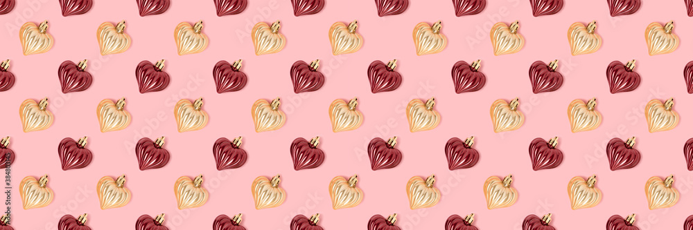Pattern made of New Year decorations in heart shape on a pink background. Creative festive concept. Pattern made of New Year decorations in heart shape on a pink background. Creative festive concept.
