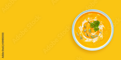 Pumpkin cream soup on color background. Top view, copy space