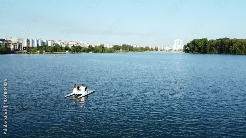 Aerial view of young lovers couple ride a catamaran in the park area of the city Aerial view of young lovers couple ride a catamaran in the park area of the city