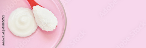Collagen white powder. Pastel color background. Health product. Woman cosmetics concept. Sport supplement. Skincare cosmetics. Horizontal banner. Pink monochrome. Cream smear. Spoon