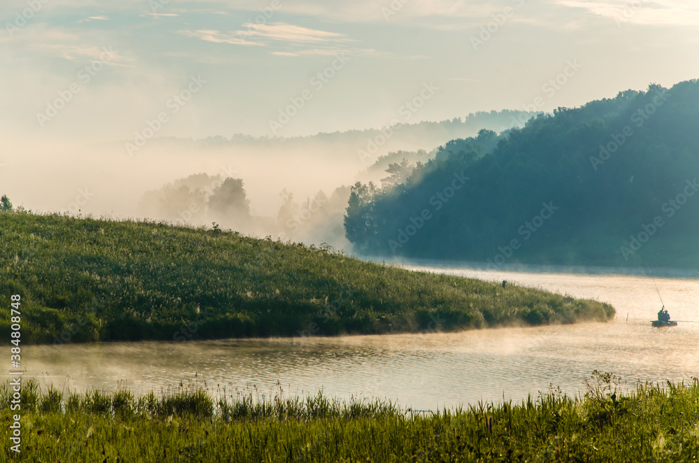 thick morning fog in the summer forest near the reservoir. fishermen on a boat