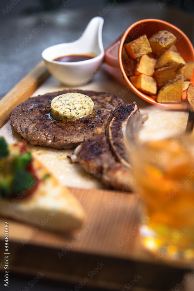 Grilled t-bone steak with grilled vegetables and whiskey glass in a restaurant table Grilled t-bone steak with grilled vegetables and whiskey glass in a restaurant table