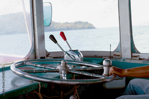 steering wheel ship and hand of boat driver inside the boat, steering wheel ship with hand holding, navigation console with metal steering wheel inside the motorboat travel at thailand photo