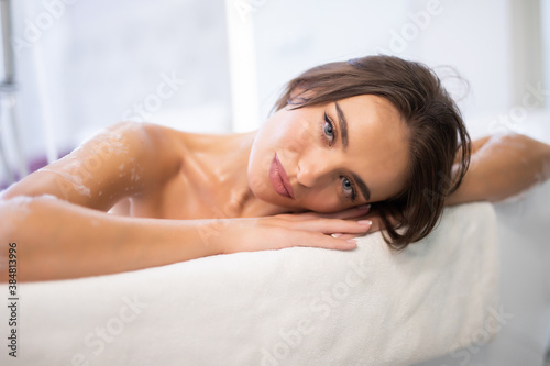Young pretty woman lying in bathtub in bathroom. Female relaxing in bathtub