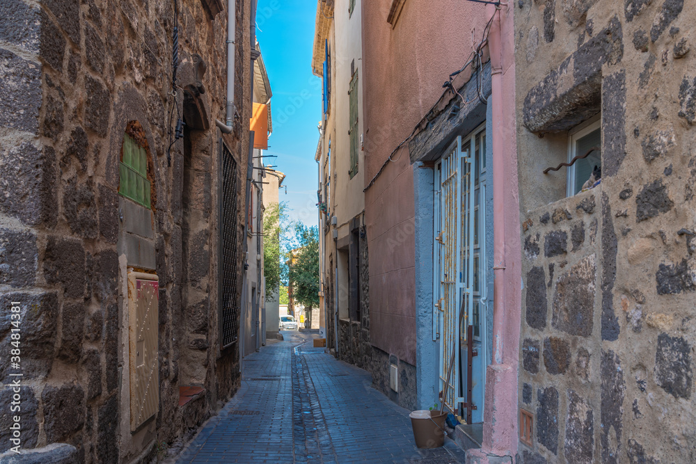 Small street at Agde Centre with old Buildings , background blue sky
