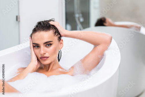 Close up hot woman lying in foam at bathroom. Sexy woman relaxing at luxury bathtub.