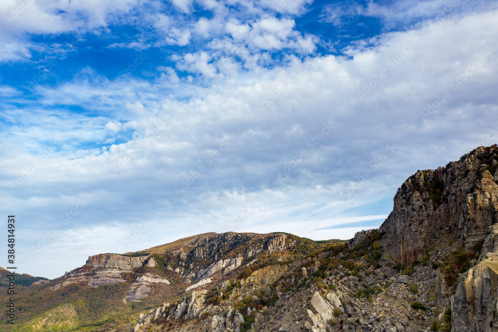 a panoramic view of the beautiful mountains with unusual ledges and rocks against the background of the sky and the valley filmed from a drone