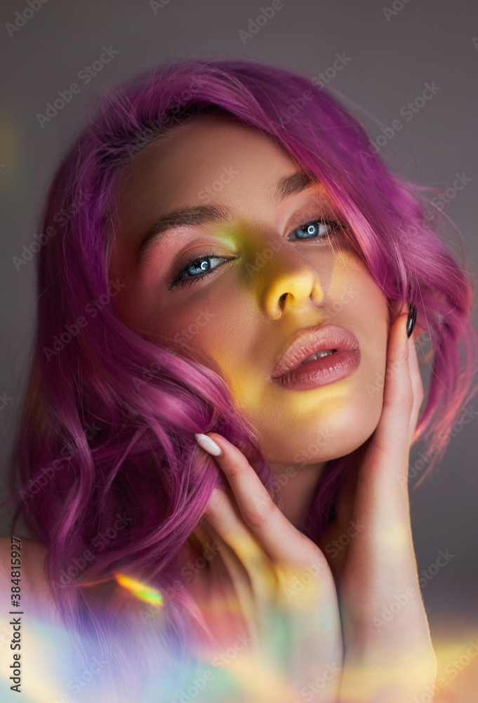 Fototapeta premium Portrait of a woman with bright colored flying hair, all shades of purple. Hair coloring, beautiful lips and makeup. Hair fluttering in the wind. Sexy woman with short hair. Professional coloring