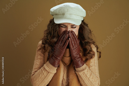 trendy woman in scarf sneezing isolated on brown background