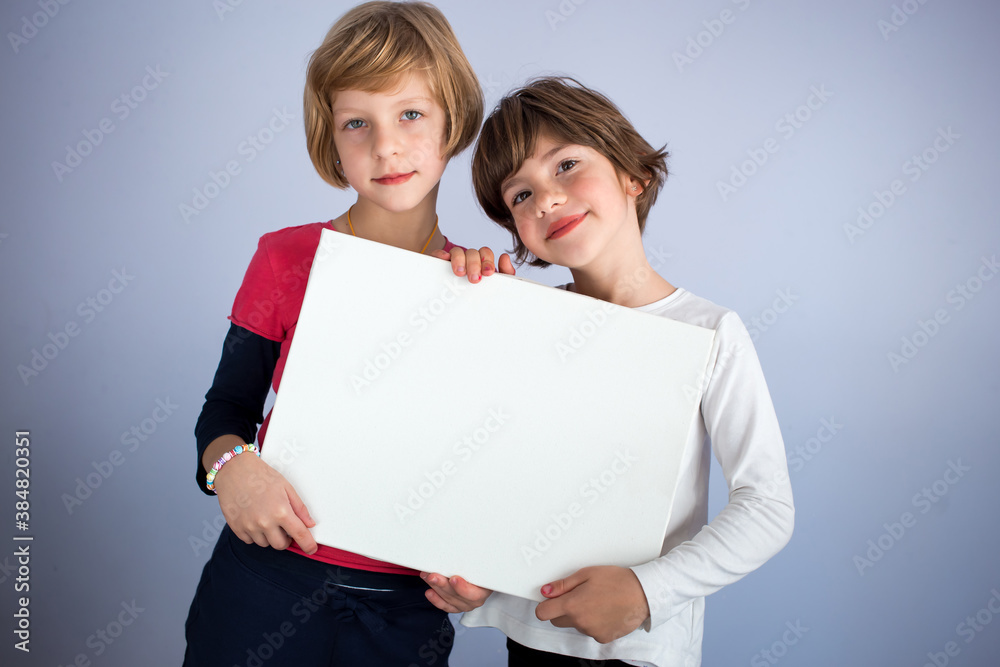 Two little girls hold empty white board. Copy space, space for writing Two little girls hold empty white board. Copy space, space for writing