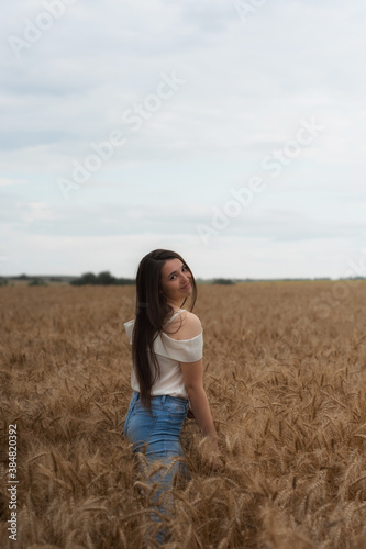Happy woman in a wheat field is laughing. Brunette with ears of wheat.