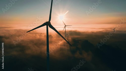 Wind turbine at sunrise in heavy fog. Wind farm generating green energy