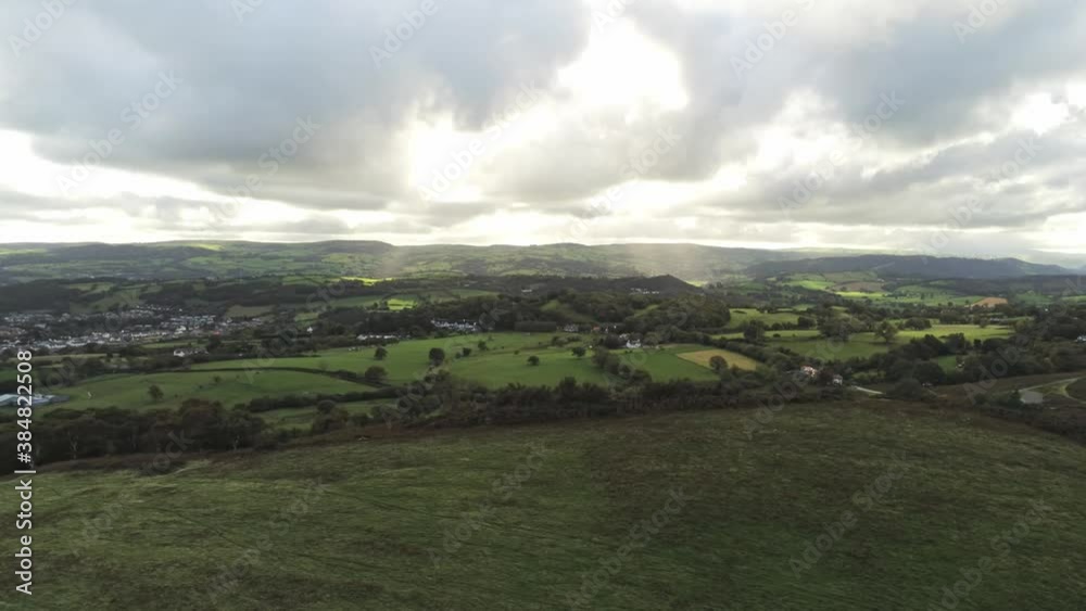 Sunbeams moving across overcast British agricultural rural village countryside morning aerial slow left pan view Sunbeams moving across overcast British agricultural rural village countryside morning aerial slow left pan view