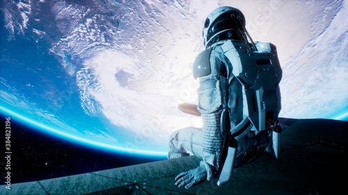 Fotografia, Obraz An astronaut sits on the wing of his spaceship and swings his legs looking at the blue planet