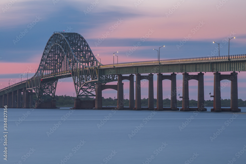 Naklejka premium Green steel bridge. The Fire Island Inlet Bridge during a colorful sunset.