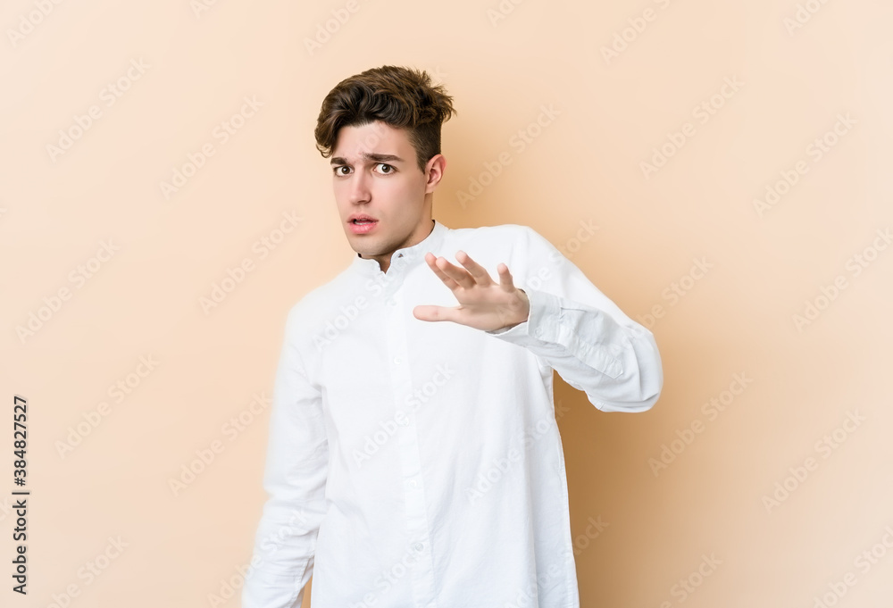 Young caucasian man isolated on beige background being shocked due to an imminent danger Young caucasian man isolated on beige background being shocked due to an imminent danger