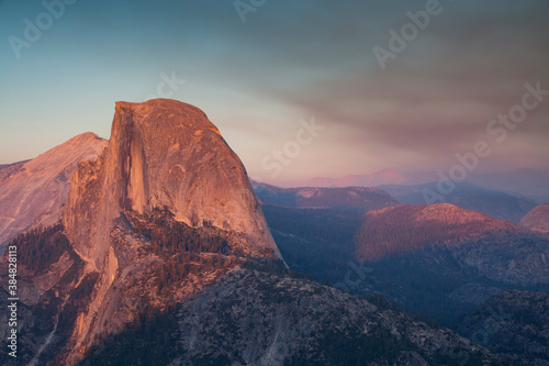 Sunset with alpine glow on the iconic Half Dome just beyond Glacier Point Road in Yosemite National Park. The sky is filled with smoke and haze from a wildfire burning inside of the park
