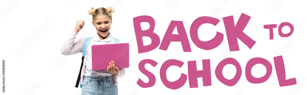 Horizontal crop of excited kid showing yeah while holding laptop near back to school lettering on white Horizontal crop of excited kid showing yeah while holding laptop near back to school lettering on white