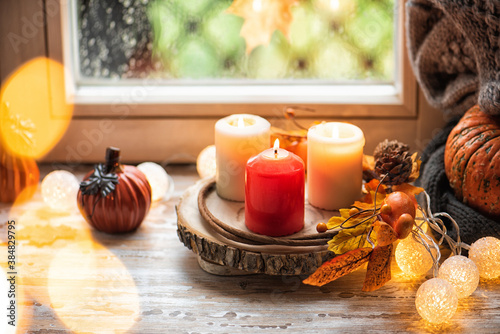 Pumpkins on the sill window  rainy weather outside. Autumn seasonal decor composition with candles light. Cozy home concept. Copy space for your text
