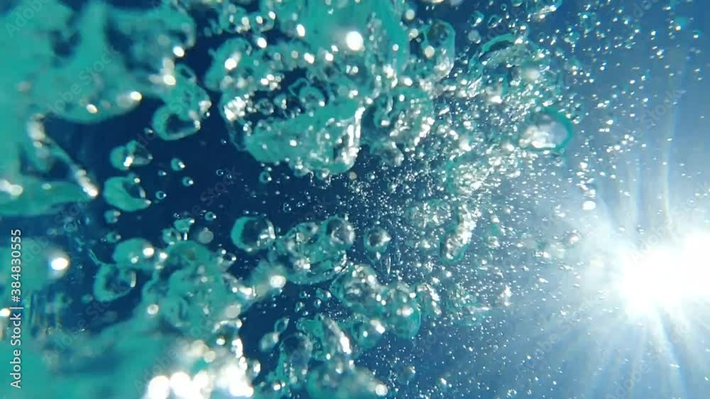 Underwater slow motion bubbles moving to surface in turquoise crystal clear pool