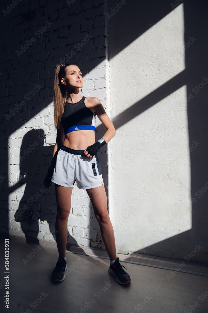 A pretty long-haired brunette of athletic build stands against a brick wall in the loft A pretty long-haired brunette of athletic build stands against a brick wall in the loft