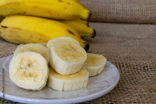 a sliced ​​banana on the plate and a bunch of bananas on the bottom. selective focus and space for text.
