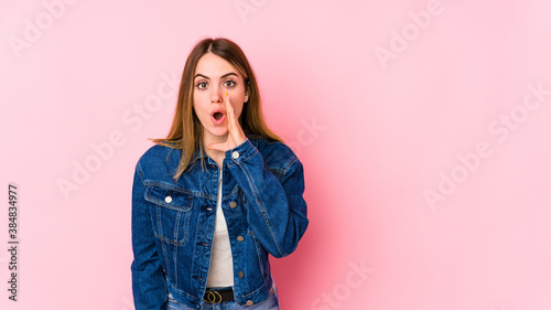 Young caucasian woman isolated on pink background is saying a secret hot braking news and looking aside © Asier