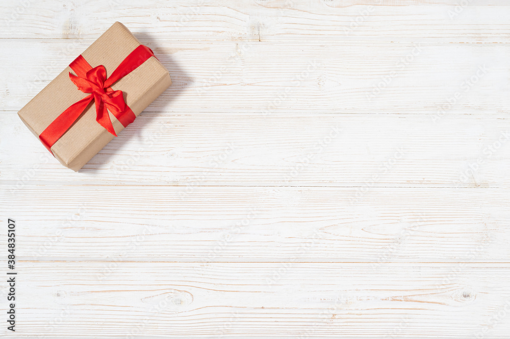 Fototapeta premium Present craft box with red decoration flat lay with copy space on the wooden white natural wooden table background