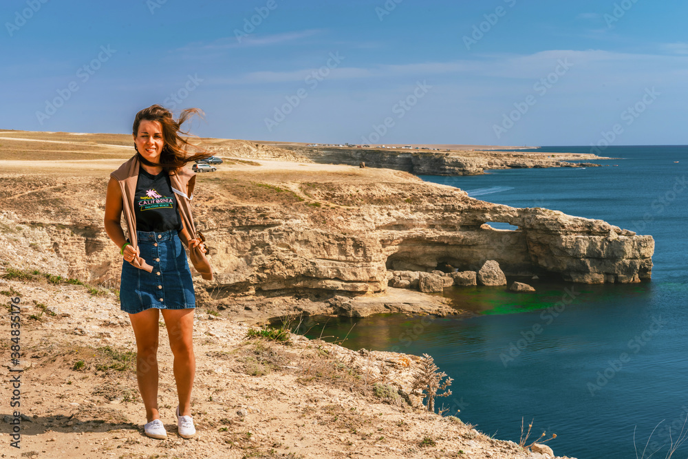 Young woman stands and looks at beautiful bright blue sea. Adventure wanderlust lifestyle