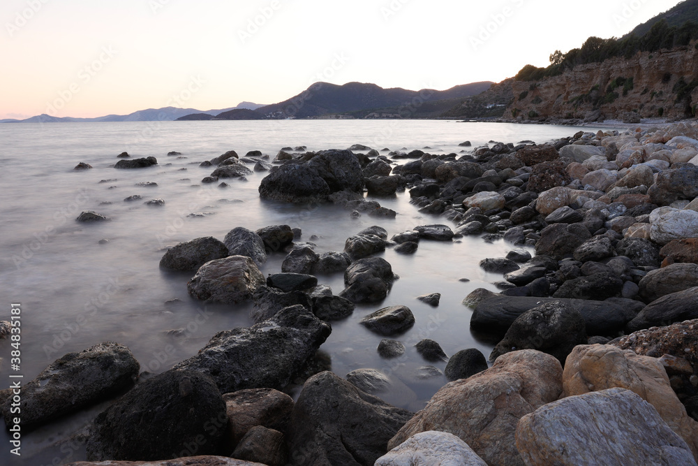 Rocky stretch of coast of the Mediterranean Sea on the Greek Aegean island of Samos with a calm water surface.