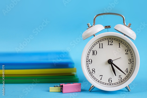 Textbooks and alarm clock on a blue background. Back to school. Concept Education or business