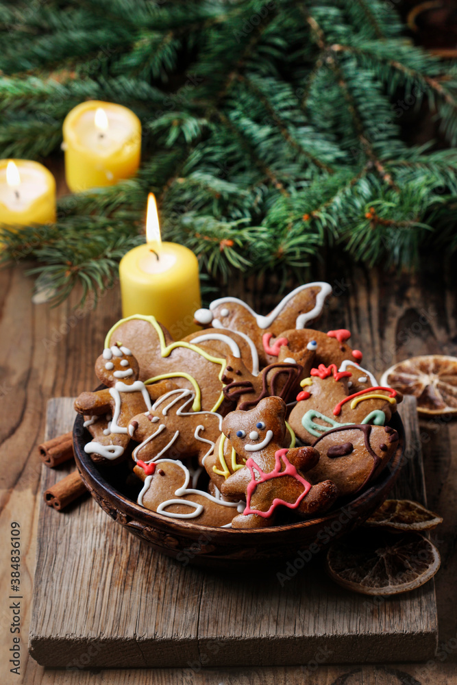 Bowl of homemade gingerbread cookies. Candles and fir in the background.