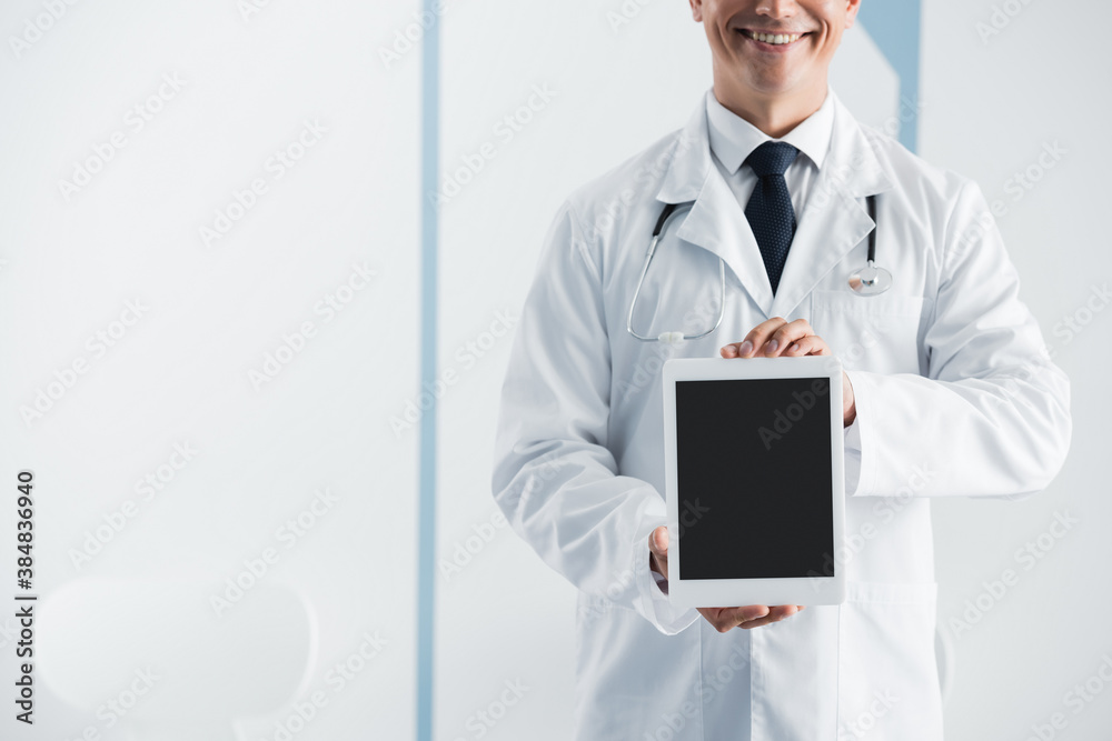 Cropped view of doctor with stethoscope showing digital tablet in clinic Cropped view of doctor with stethoscope showing digital tablet in clinic