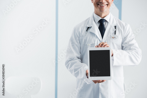 Cropped view of doctor with stethoscope showing digital tablet in clinic