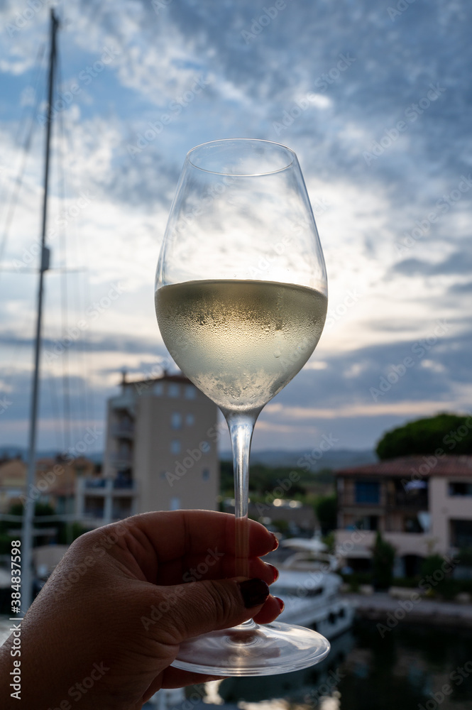 Obraz premium Tasting of local white wine in summer with sail boats haven of Port Grimaud on background, Provence, France