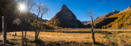 Lac des Sagnes in Autumn with La Tour des Sagnes pyramidal shaped mountain in the Mercantour National Park (panoramic). Jausiers, Ubaye Valley, Alpes de Haute Provence, Alps, France photo