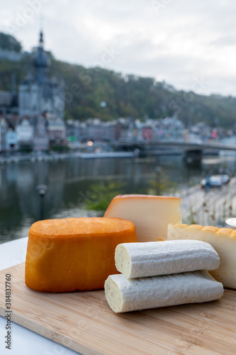 Cheese collection, Belgian abbey cheeses made with brown trappist beer and fine herbs and view on Maas river in Dinant, Wallonia, Belgium photo