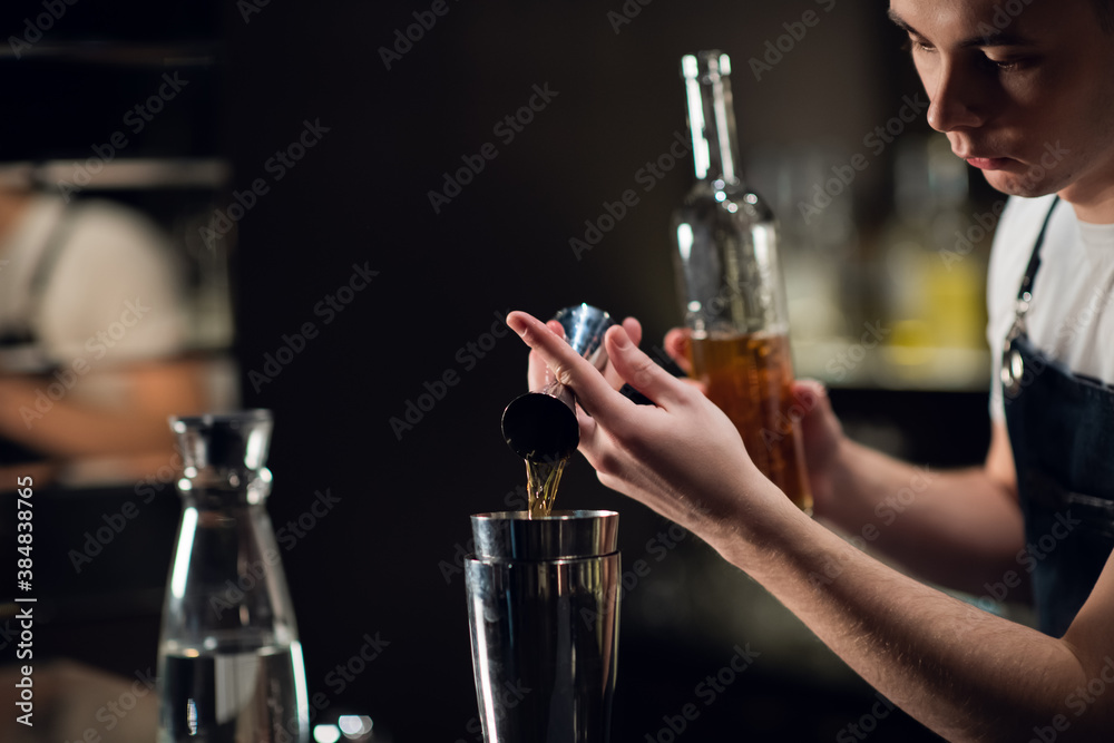Close-up of the process of preparing a cocktail with liqueur at a party of friends in a nightclub. The dark blurred background