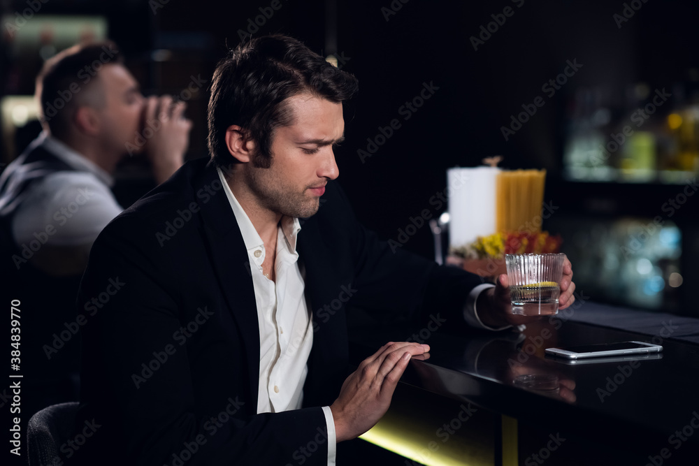 a young man drank a lot at the bar, sitting drunk at the bar with a cocktail.