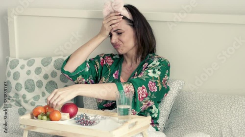 Sick, unhappy woman in pyjamas sitting in bed, 4K 

