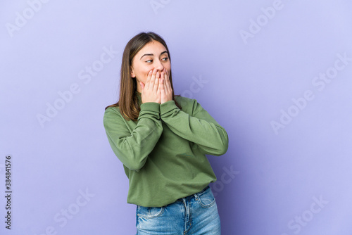 Young caucasian woman laughing about something, covering mouth with hands.