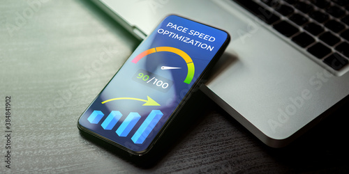 Mobile Page Speed Optimization concept. Website Loading Time image for internet SEO. Mobile phone lying on a black wooden table next to the laptop and on the screen accelerometer with high values