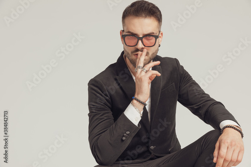 Attractive fashion model gesturing silence, wearing sunglasses