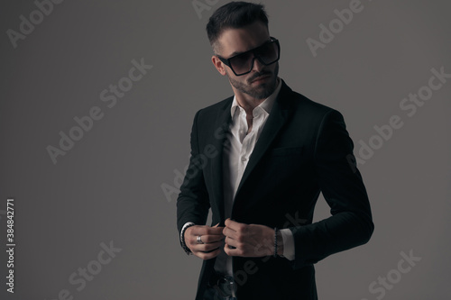 Mysterious fashion model closing his jacket, wearing sunglasses