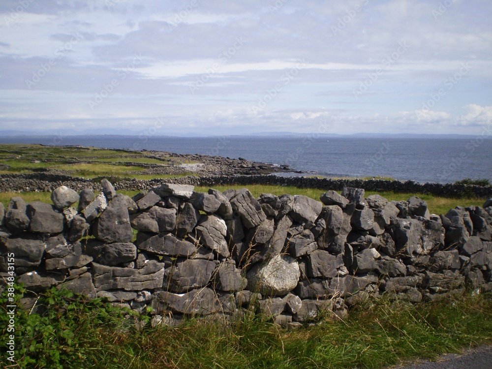 Stone wall, green grass and blue sea in irish landscape