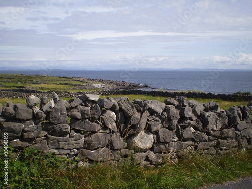 Stone wall  green grass and blue sea in irish landscape